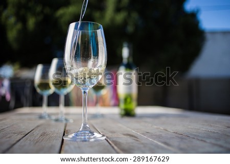 Close up wide angle  shot of a glass of white whine on a rustic table outside with natural light