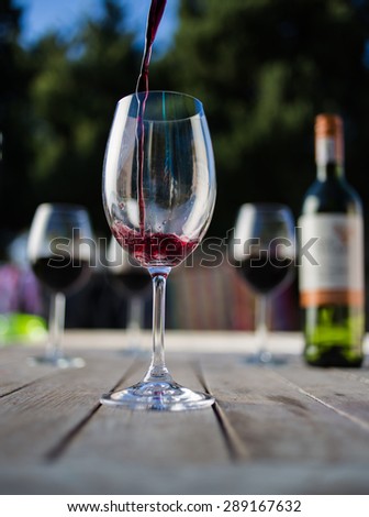 Close up wide angle   shot of a glass of red whine on a rustic table outside with natural light
