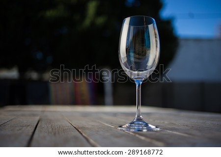 water being poured into a wine glass on a rustic table outside with natural light.