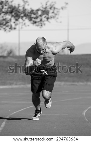 Male Athelete sprinting on a tartan athletics track on a bright sunny day