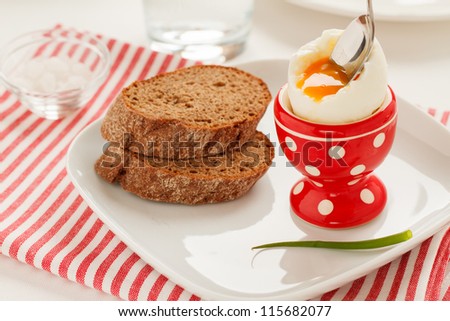 Soft-boiled egg in a red egg cup and whole grain bread