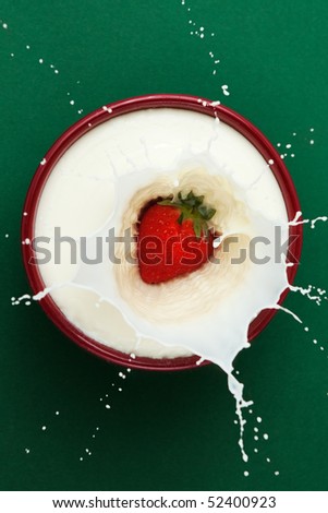 Strawberry dropped into bowl of milk, creating a splash sculpture