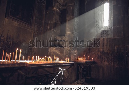 Old Armenian christian church interior with sun rays from the window falling on the candles. Religion, old architecture, christianity, travel, belief concept.