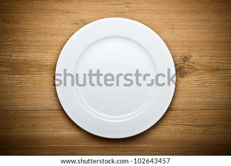 Empty white plate on wooden table Empty white plate on wooden table