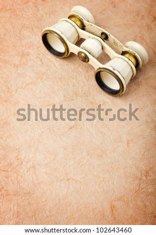 Old binoculars on vintage paper background