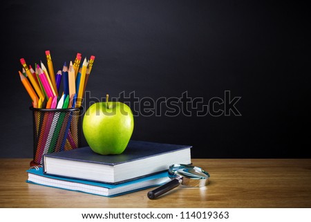 Teacher\'s desk with a color pencil, notebook and other equipment.