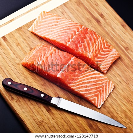 salmon fillet with knife on wood board