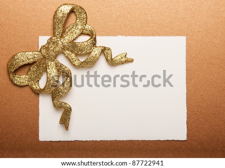 Blank gift tag tied with a gold bow on gold paper