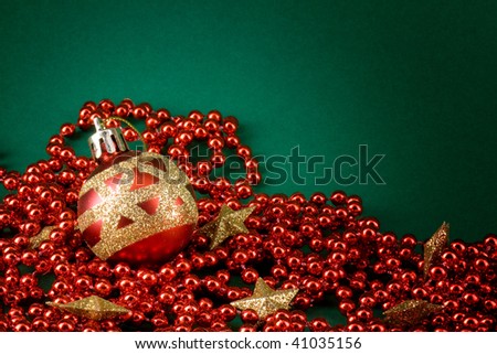 Red christmas globe, red pearls and golden stars over green background