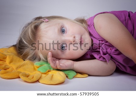 Little girl ready to take a nap on a yellow pillow