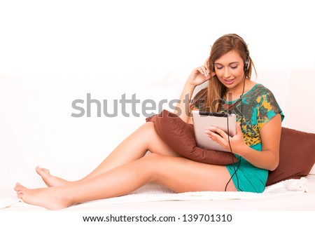 Beautiful teenager relaxing on the couch with the company of a last generation tablet computer