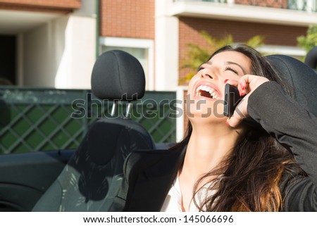 A young successful business woman at the phone in her brand new convertible sports car