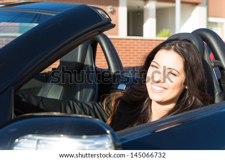 A young successful business woman in a luxurious convertible sports car