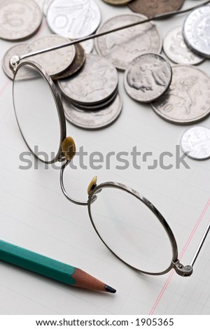 rimmed glasses and different coins on math paper