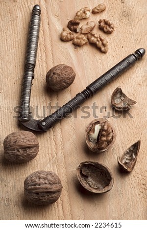 walnuts scattered over wood surface with nutcracker
