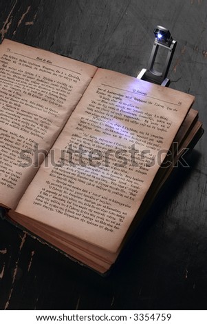an old book illuminated by pop-up reading lamp