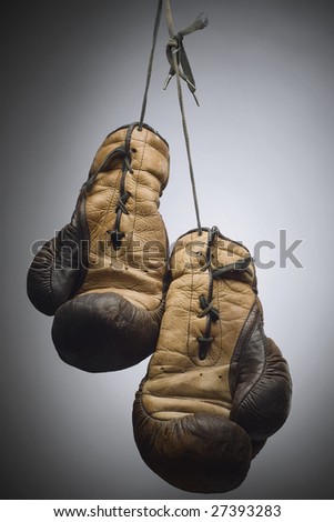 a pair of worn boxing gloves hanging on the string