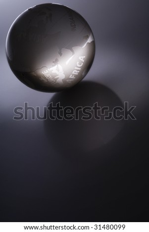 a glass globe glowing in dark - word Africa illuminated - with reflection