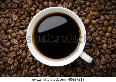 a white cup of filter coffee on coffee beans