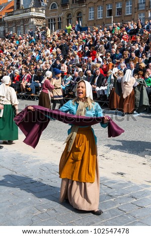 IEPER, BELGIUM - MAY 13, 2012: Woman dressed as medieval weaver presents cloth in the 43th edition of the Cat Parade in Ieper, Belgium on May 13, 2012