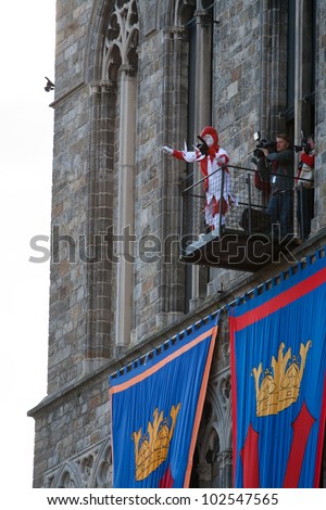 IEPER, BELGIUM - MAY 13, 2012: Joker throws a black plush cat toy from a small balcony of the city hall tower at the 43th edition of the Cat Parade in Ieper, Belgium on May 13, 2012