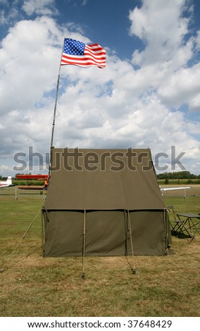 American army tent on the airfield with american flag and fragments of planes behind