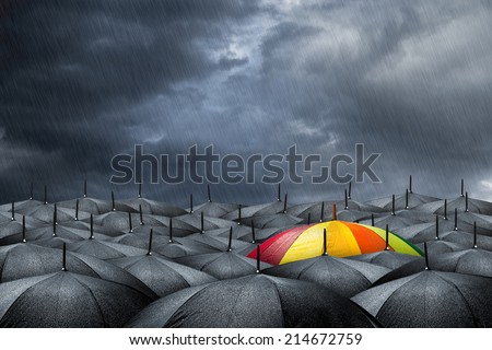 rainbow umbrella in mass of black umbrellas