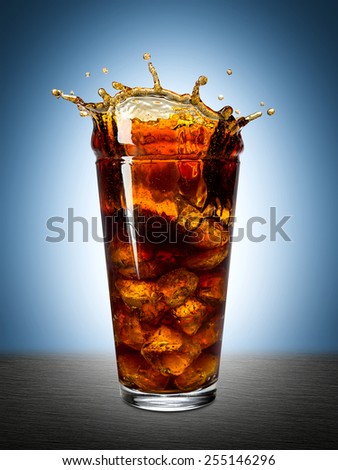 ice splashes into glass of cola