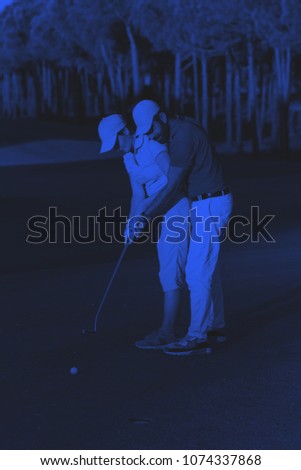 male golf instructor teaching female golf player, personal trainer giving lesson on golf course duo tone