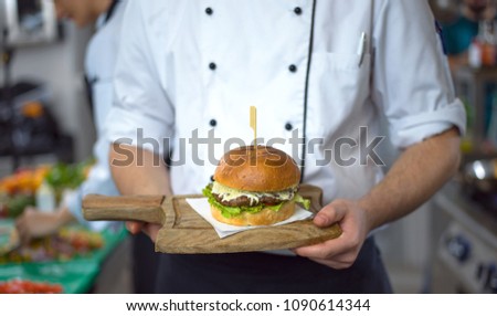 master chef putting toothpick on a burger in  restaurant kitchen