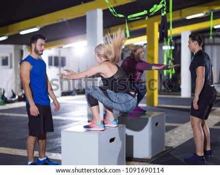 group of young healthy athletic people training jumping on fit box at gym