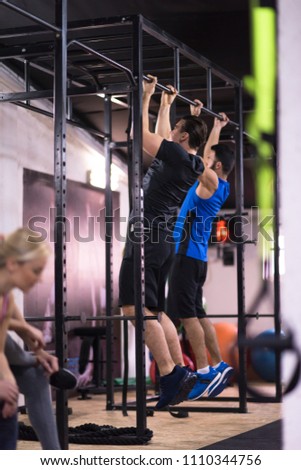 group of young muscular athletes doing pull ups on the horizontal bar as part of Cross fitness Training