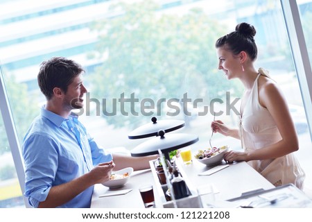 A young couple sitting at a table and have lunch at an outdoor restaurant