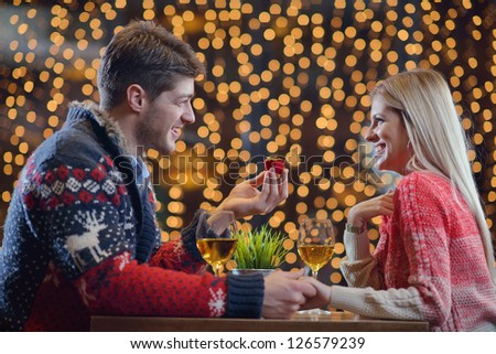 The young man gives a wedding ring   gift to  girl in restaurant