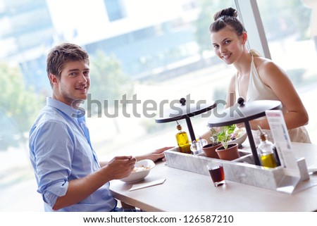 A young couple sitting at a table and have lunch at an outdoor restaurant
