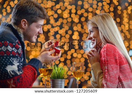 The young man gives a wedding ring   gift to  girl in restaurant