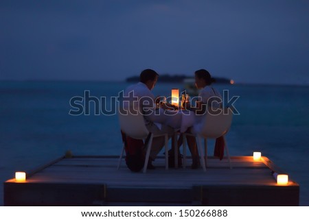 Romantic Couple In Love Have Dinner In Outdoor Restaurant With Candles With Sea In Background