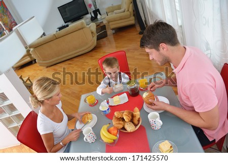 happy young family have healthy breakfast at kitchen with red details on bright morning light