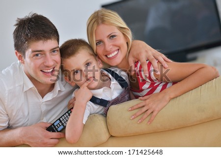 Happy Young Family With Kids In Bright Modern Living Room Have Fun And Looking Big Flat Lcd Tv