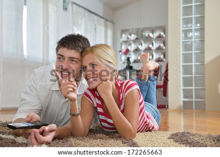 Relaxed young  couple watching tv at home in bright living room