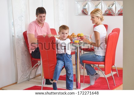 happy young family have healthy breakfast at kitchen with red details on bright morning light
