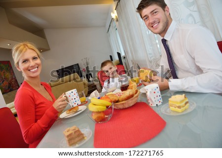 Happy Young Family Have Healthy Breakfast At Kitchen With Red Details On Bright Morning Light