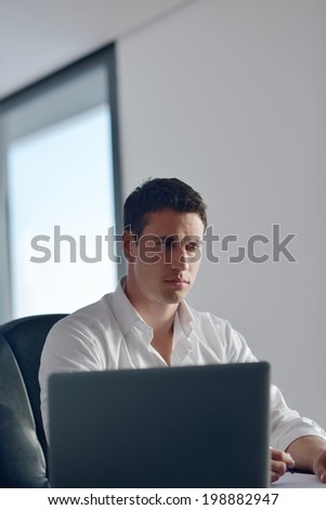 portrait of young happy business man working on laptop computer at home