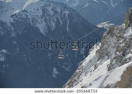winter landscape with ski chairlift cabin and mountain covered with snow at sunny day