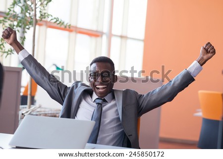 Happy smiling successful African American businessman  in a suit in a modern bright office indoors