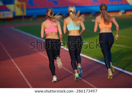 athlete woman group  running on athletics race track on soccer stadium and representing competition and leadership concept in sport