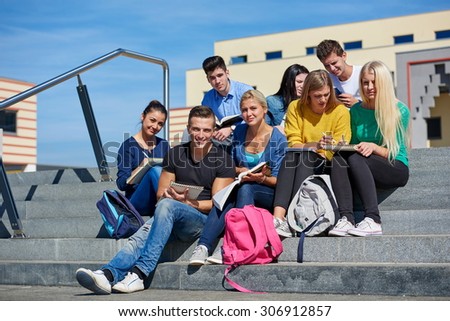 Group portrait  of happy  students outside in front of school sitting on steps have fun
