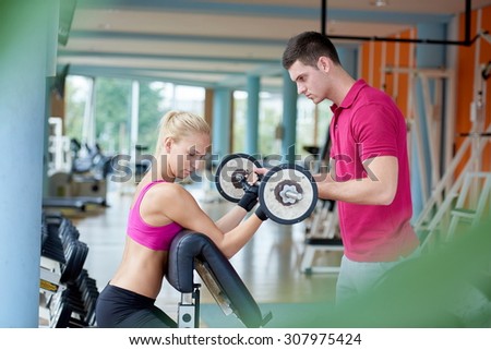 young sporty woman with trainer exercise weights lifting in fitness gym