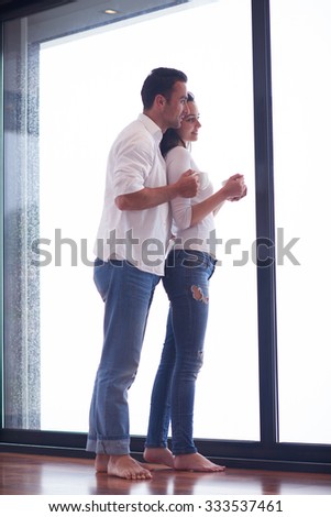 relaxet young couple drink first morning coffee  over big bright window in moder home villa interior