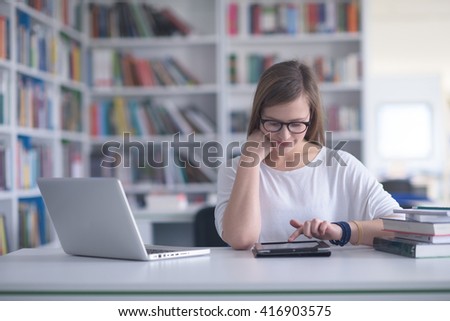 female student study in school library, using laptop and searching for information on internet